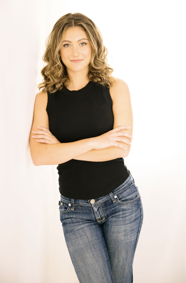 Tulia Henderson, commercial headshot: arms folded, a soft closed-lip smile, against a white background.